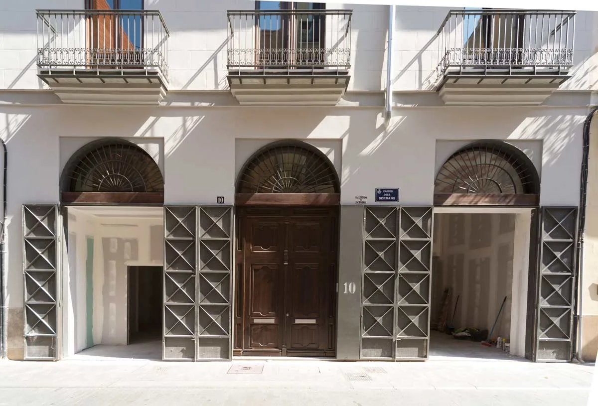 Puertas plegables de chapa en los accesos al bajo comercial