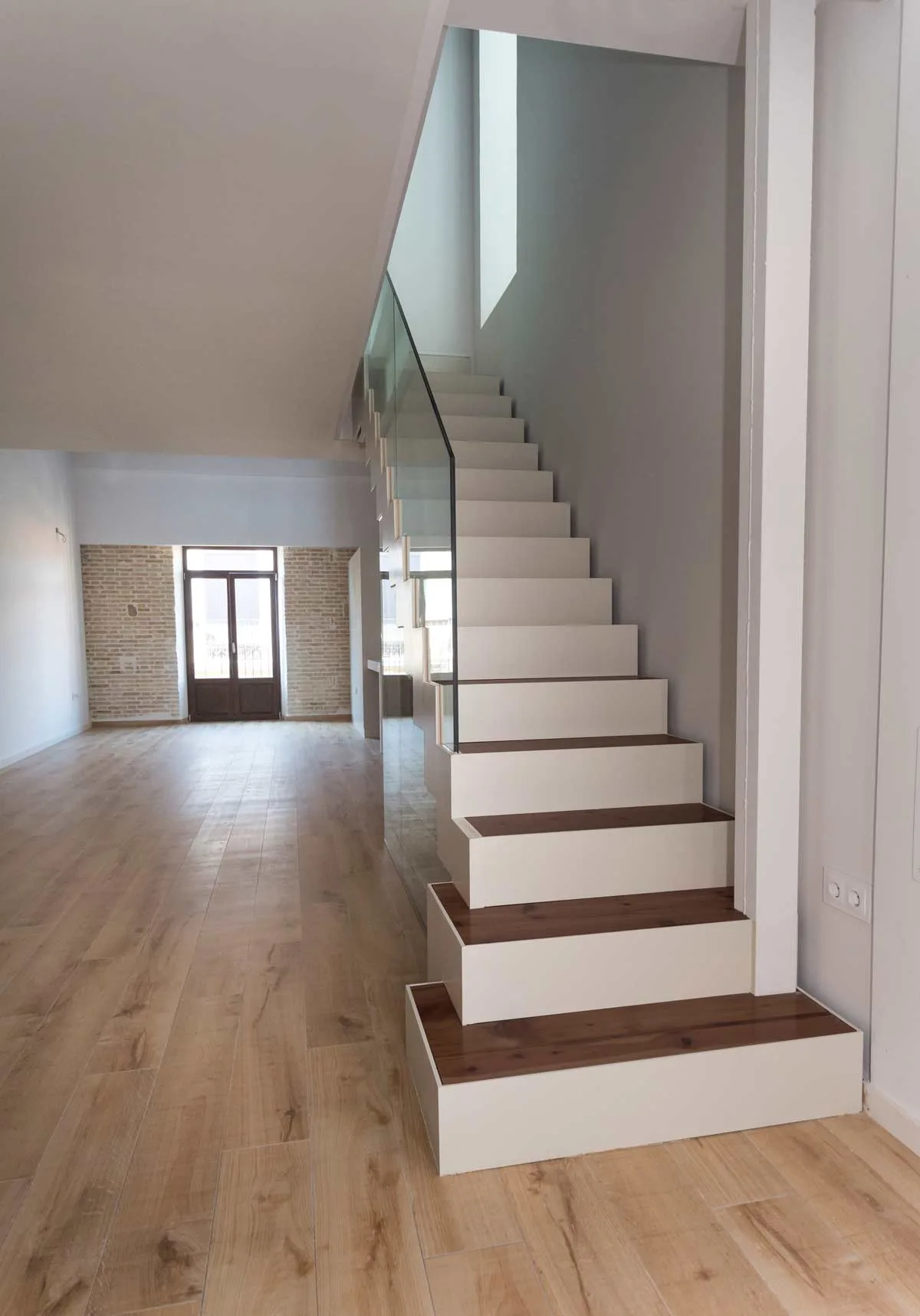 Escalera del ático dúplex con peldaños de madera y barandilla de cristal