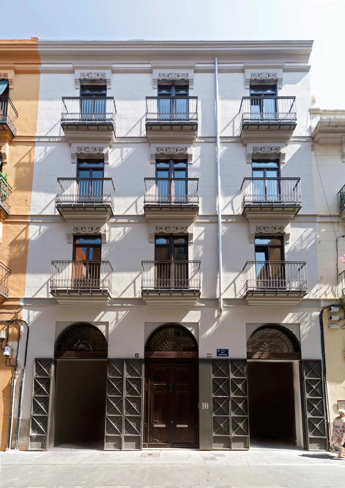 Fachada rehabilitada del edificio, con los balcones de hierro forjado y los ventanales de madera