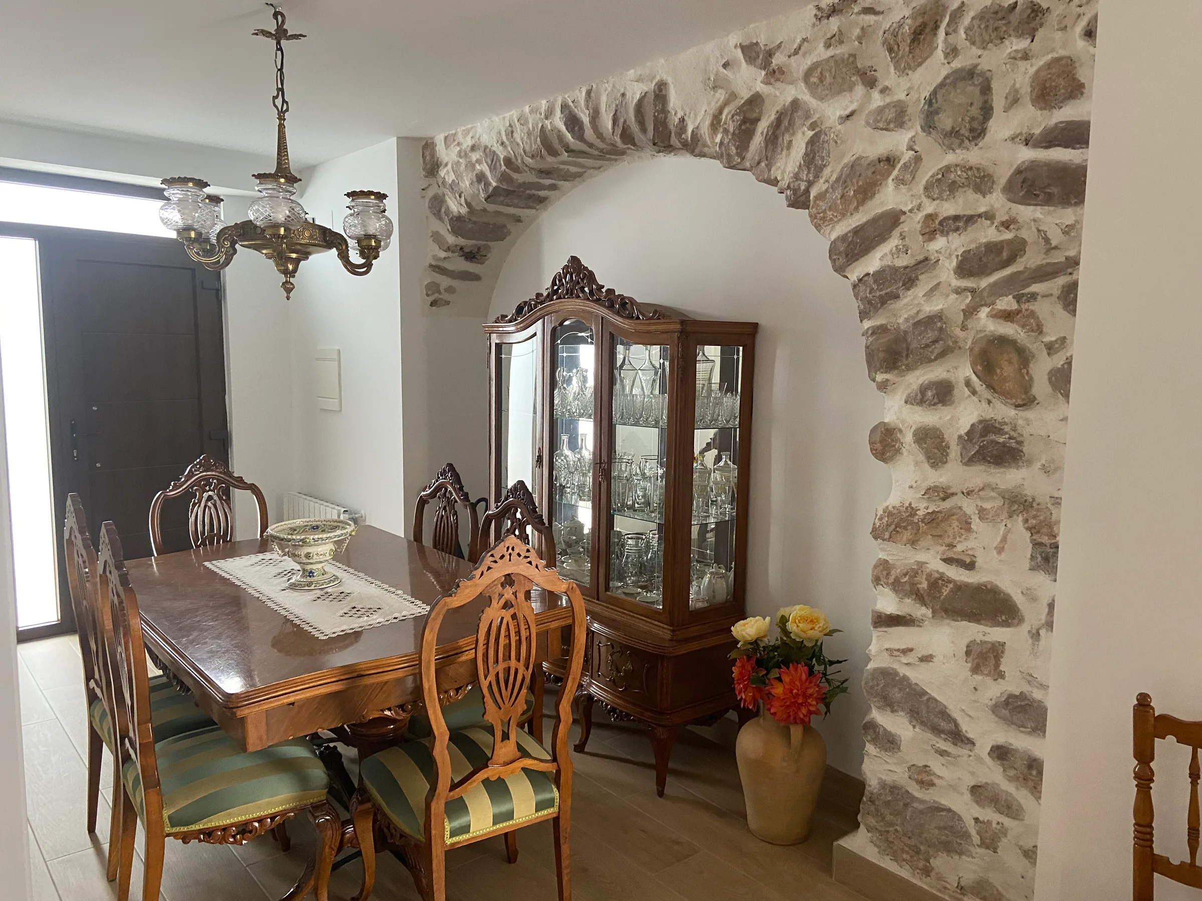 Comedor con mobiliario de anticuario junto al arco de piedra natural