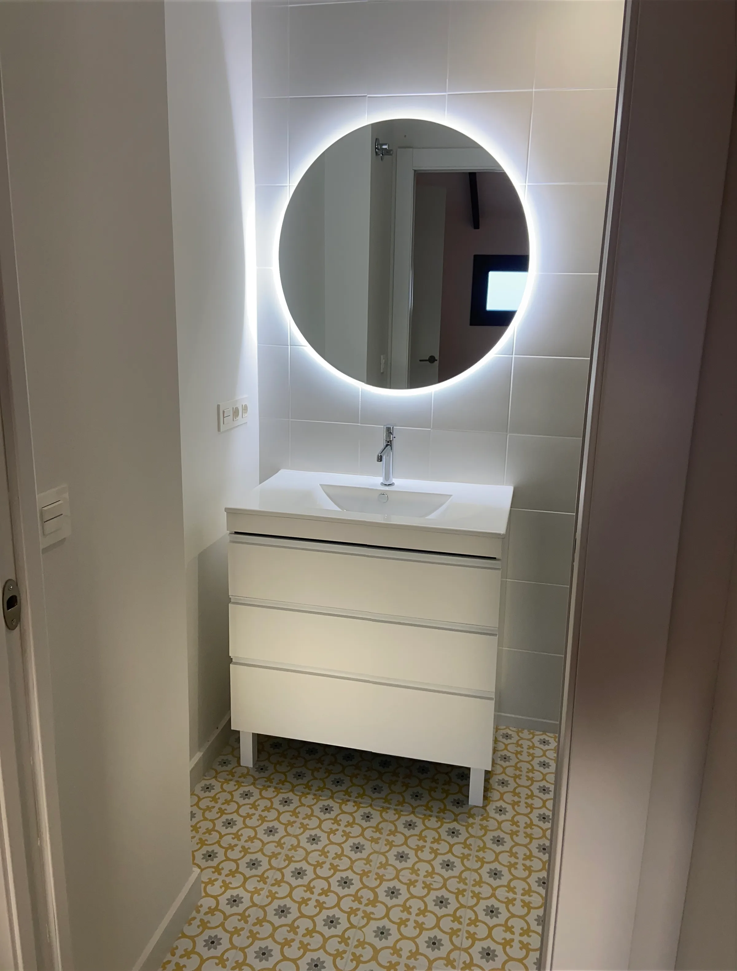 Lavabo con espejo circular retroiluminado