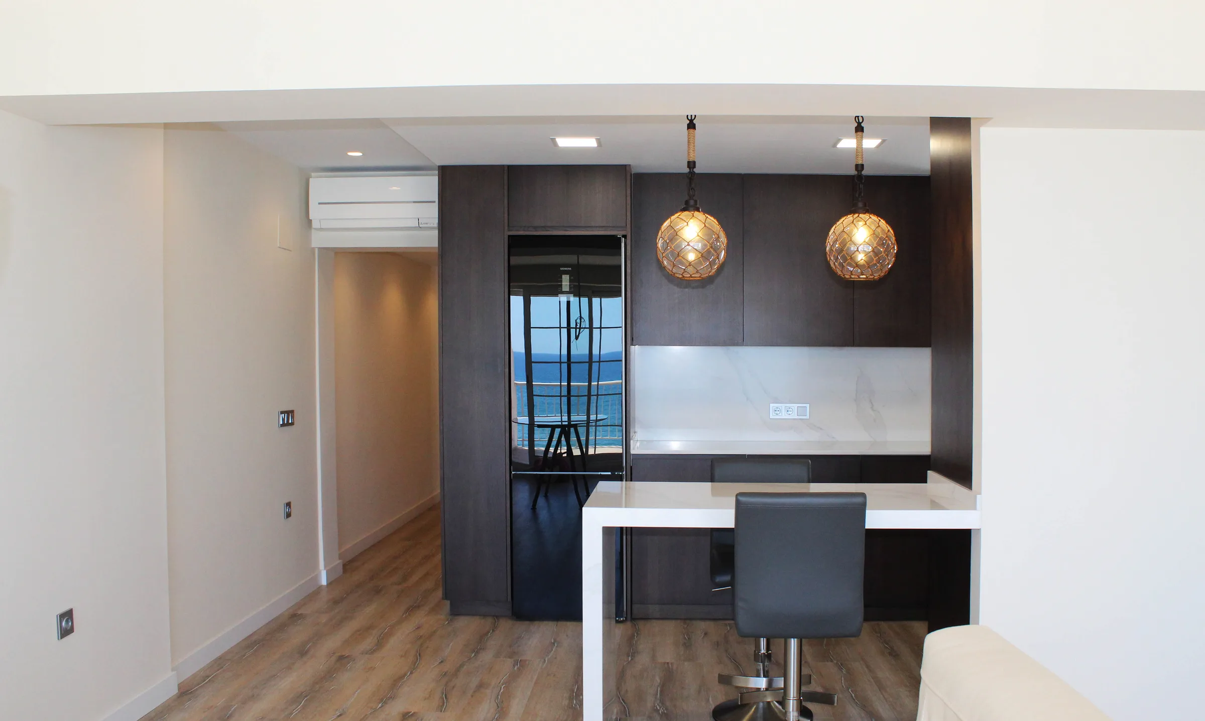 Cocina abierta al salón con barra e iluminación suspendida