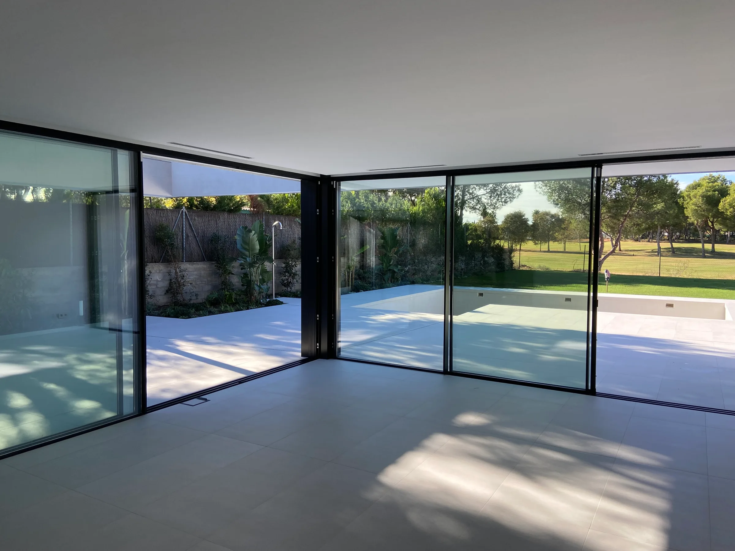 Salón con ventanales de esquina abiertos a la piscina y al campo de golf