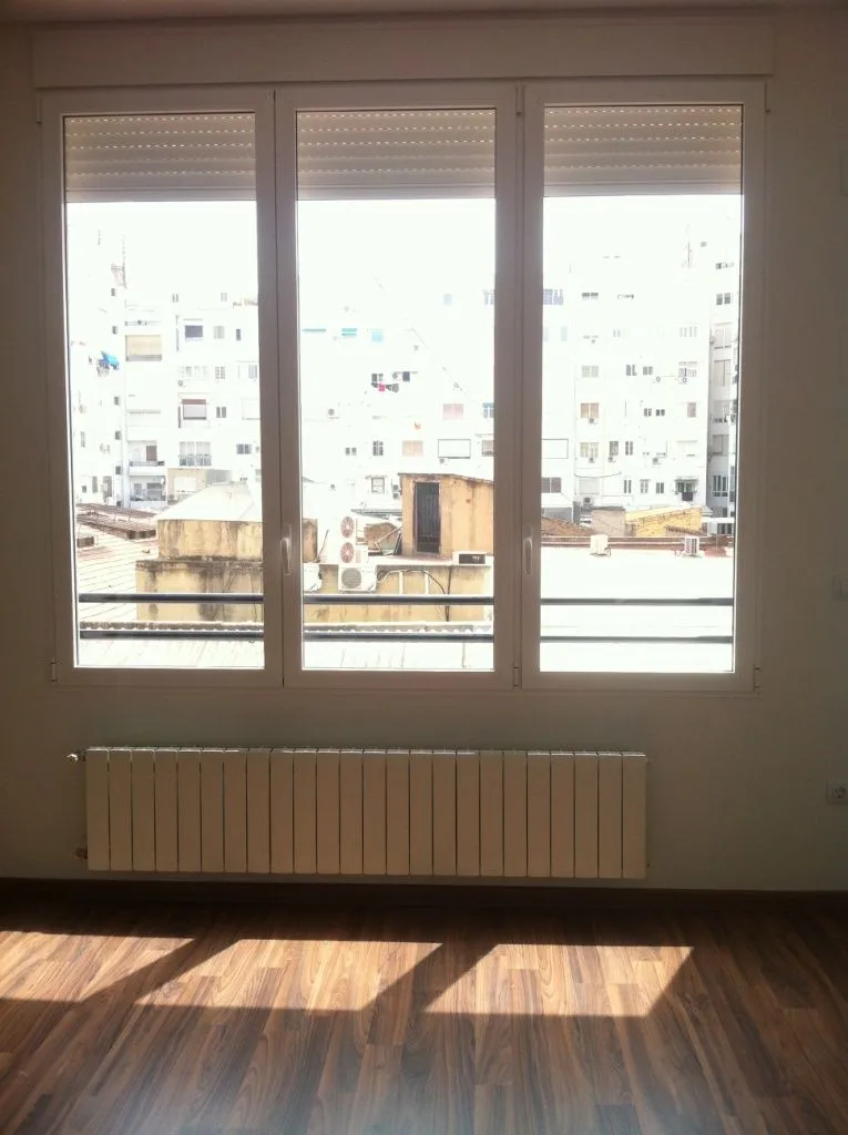 Dormitorio con ventana de tres hojas y radiador bajo el alféizar