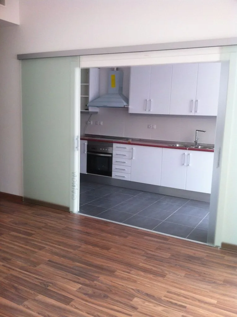 Salón con la puerta corredera acristalada abierta hacia la cocina