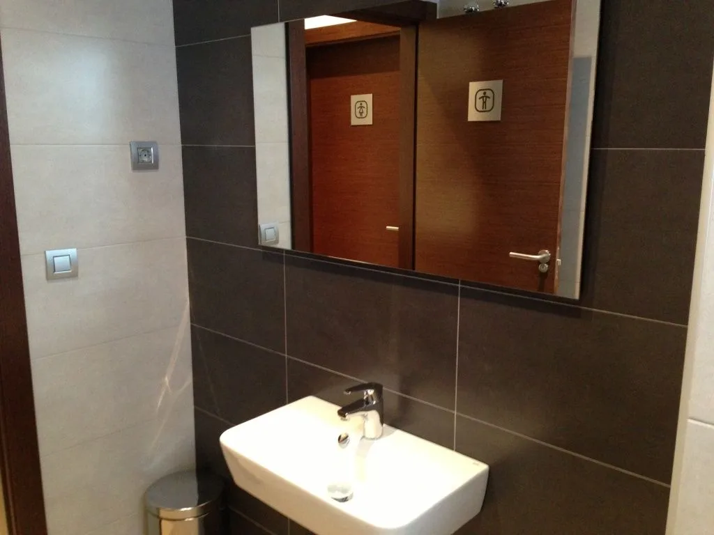 Aseo con lavabo suspendido y espejo sobre alicatado de gran formato