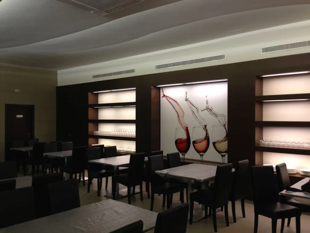 Zona de comedor con las estanterías retroiluminadas y las mesas vestidas